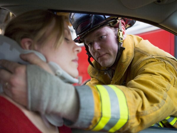 Firefighter helping an injured woman in a car